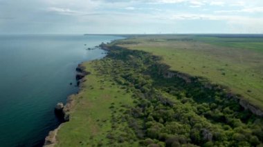 Yeşil alanlar ve ağaçlarla kaplı kayalık kayalık kıyı şeridinin panoramik videosu. Karadeniz kıyısında bahar zamanı, Yailata - Bulgaristan 'ın ulusal arkeoloji ve doğa rezervi.