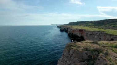 Anne ve kızının yeşil tarlaları ve ağaçları olan kayalık kıyılarda yürüdüğü panoramik bir video. Yailata - Bulgaristan 'ın ulusal arkeoloji ve doğa rezervi.