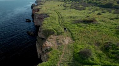 Anne ve kızının yeşil tarlaları ve ağaçları olan kayalık kıyılarda yürüdüğü panoramik bir video. Yailata - Bulgaristan 'ın ulusal arkeoloji ve doğa rezervi.