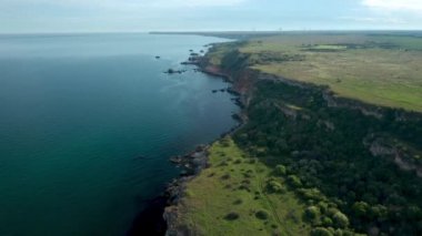 Yeşil alanlar ve ağaçlarla kaplı kayalık kayalık kıyı şeridinin panoramik videosu. Karadeniz kıyısında bahar zamanı, Yailata - Bulgaristan 'ın ulusal arkeoloji ve doğa rezervi.
