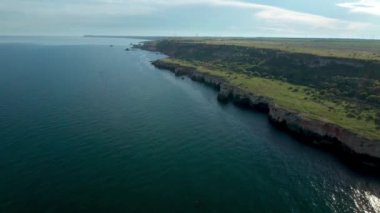 Yeşil alanlar ve ağaçlarla kaplı kayalık kayalık kıyı şeridinin panoramik videosu. Karadeniz kıyısında bahar zamanı, Yailata - Bulgaristan 'ın ulusal arkeoloji ve doğa rezervi.