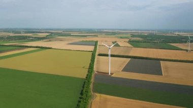 Bahar tarlaları boyunca rüzgar türbinlerinin etrafında uçan hava. Temiz ve Yenilenebilir Rüzgâr Güç Çiftliği hareket halinde. Yeşil enerji, sürdürülebilir alternatif elektrik, kirlilik ortamı yok.