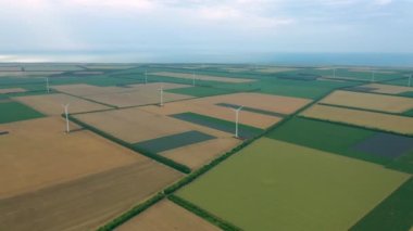 Yaz tarlaları boyunca rüzgar türbinlerinin üzerinde uçan hava. Temiz ve yenilenebilir rüzgar enerjisi çiftliği hareket halinde. Yeşil enerji, sürdürülebilir alternatif elektrik, kirlilik ortamı yok.