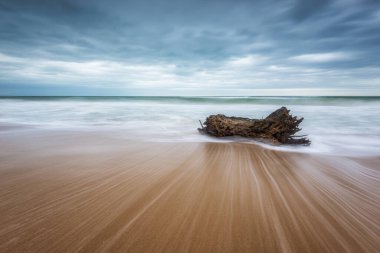 Kumlu bir sahilde fırtınalı bir sabahla inanılmaz bir deniz manzarası ve yavaş bir kepenk ve dalgalar
