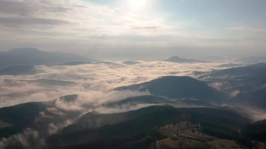 Alçak bulutlar ve sabah sisleri üzerinden insansız hava aracı uçuşu güneş doğarken dağları kapladı, Bulgaristan 'daki Rodop Dağları