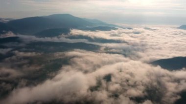 Alçak bulutlar ve sabah sisleri üzerinden insansız hava aracı uçuşu güneş doğarken dağları kapladı, Bulgaristan 'daki Rodop Dağları