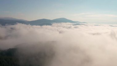 Alçak bulutlar ve sabah sisleri üzerinden insansız hava aracı uçuşu güneş doğarken dağları kapladı, Bulgaristan 'daki Rodop Dağları