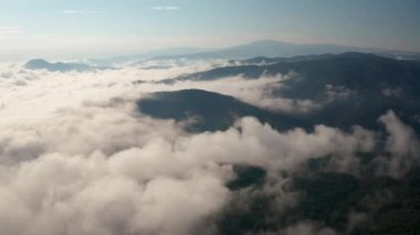 Alçak bulutlar ve sabah sisleri üzerinden insansız hava aracı uçuşu güneş doğarken dağları kapladı, Bulgaristan 'daki Rodop Dağları