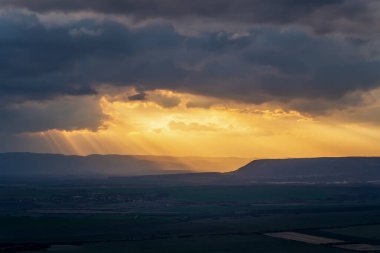 Gün batımında yeşil tarlaların üzerinde güneş ve güneş ışınlarının inanılmaz uzun görüntüsü.