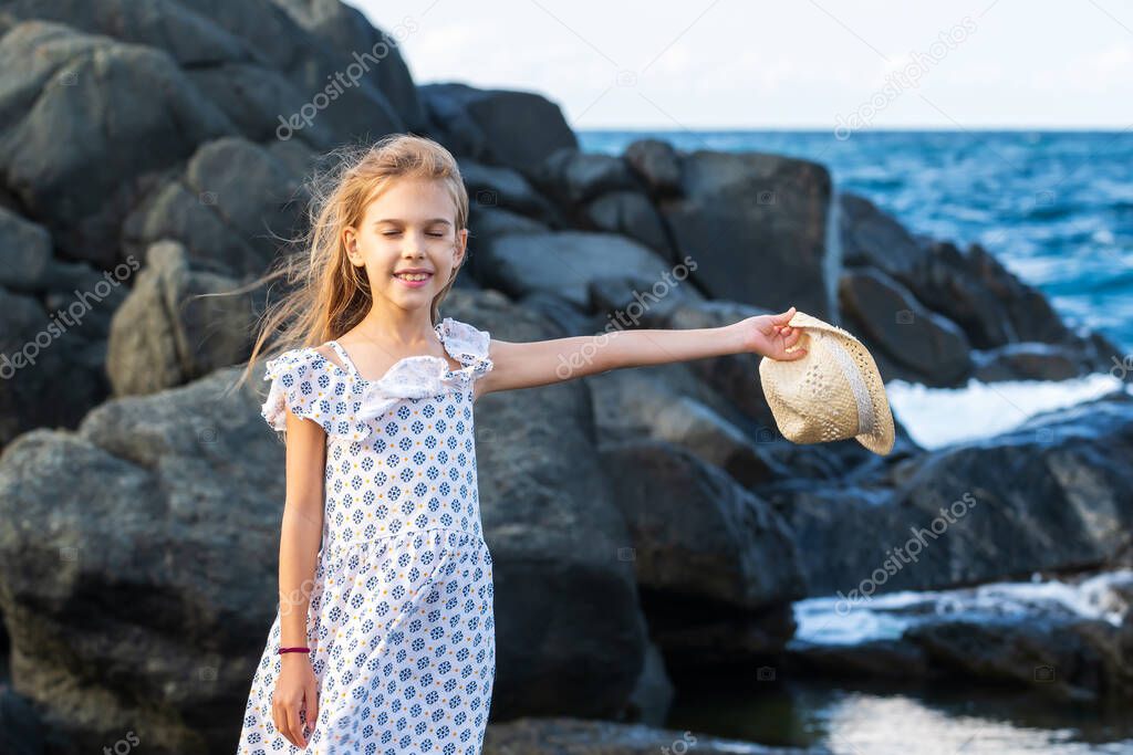 A pretty little girl enjoys the sunny warm day at a rocky coastline