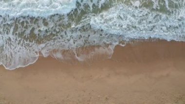 Pahalı deniz dalgaları, Karadeniz kıyısı, Bulgaristan yakınlarındaki saman güneşlikleri ve güneşlikleriyle boş ve güzel kumlu bir plajın üzerindeki video.