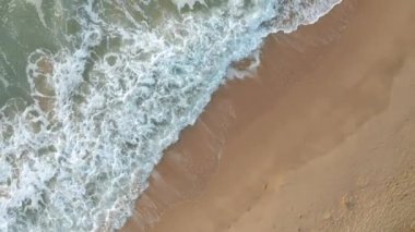 Pahalı deniz dalgaları, Karadeniz kıyısı, Bulgaristan yakınlarındaki saman güneşlikleri ve güneşlikleriyle boş ve güzel kumlu bir plajın üzerindeki video.
