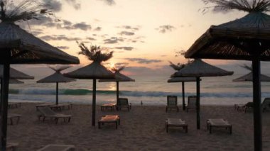 Gün doğumunda boş bir kumsalda saman güneş gözlüklü ve güneşli bir video.