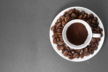 bir tabak ile kahve bitkisinden meyve ile taze çekilmiş kavrulmuş kahve çekirdekleri ile bir fincan.