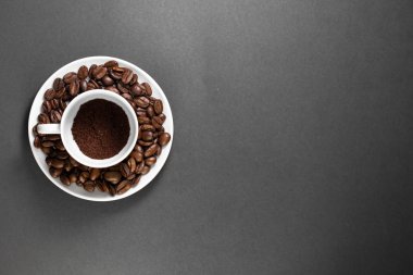 bir tabak ile kahve bitkisinden meyve ile taze çekilmiş kavrulmuş kahve çekirdekleri ile bir fincan.