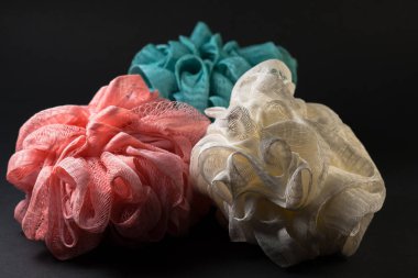 Siyah bir arka plan üzerinde, üç duş süngeri yerleştirilir ve gerilir, sunumun ortasında.