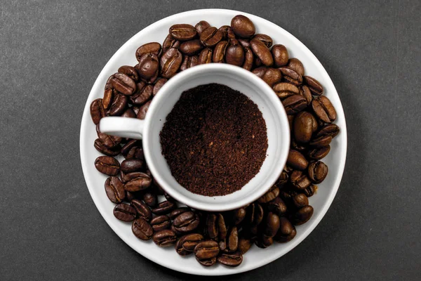 Une tasse avec des grains de café torréfiés fraîchement moulus avec des fruits du café — Photo