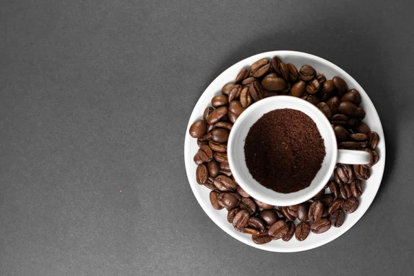 Une tasse avec des grains de café torréfiés fraîchement moulus avec des fruits de la plante de café avec une assiette . — Photo