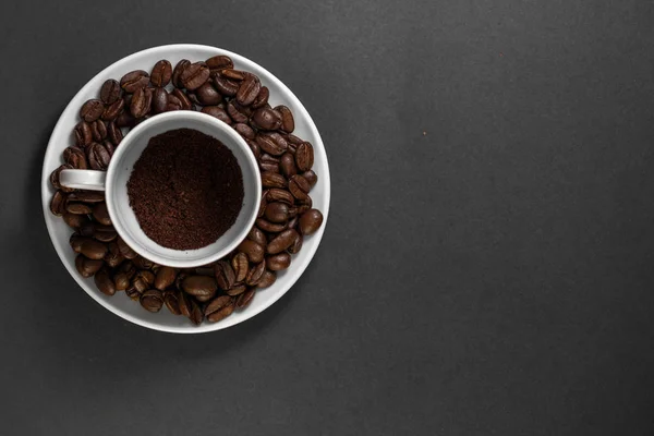 Une tasse avec des grains de café torréfiés fraîchement moulus avec des fruits de la plante de café avec une assiette . — Photo