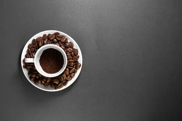 Une tasse avec des grains de café torréfiés fraîchement moulus avec des fruits de la plante de café avec une assiette . — Photo