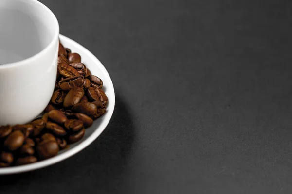 Une tasse avec des grains de café torréfiés fraîchement moulus avec des fruits de la plante de café avec une assiette . — Photo