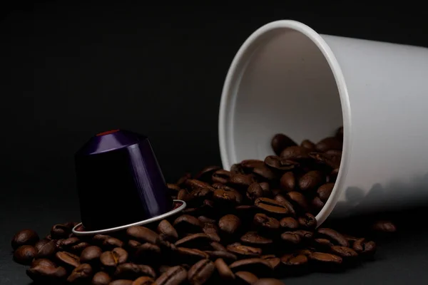 Tasse en plastique de café blanc couché, sur un fond noir, avec des grains de café brun à l'intérieur du verre. Cafétéria et nourriture . — Photo