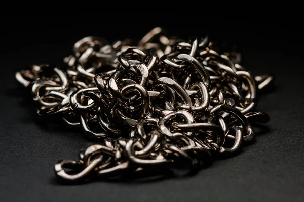 Chromed silver chains on a black background. Long and careful. Jewelry.