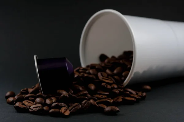 Műanyag csésze fehér kávé feküdt, az egész fekete háttér, barna kávébab belsejében az üveg. Kávézó és élelmiszer. — Stock Fotó