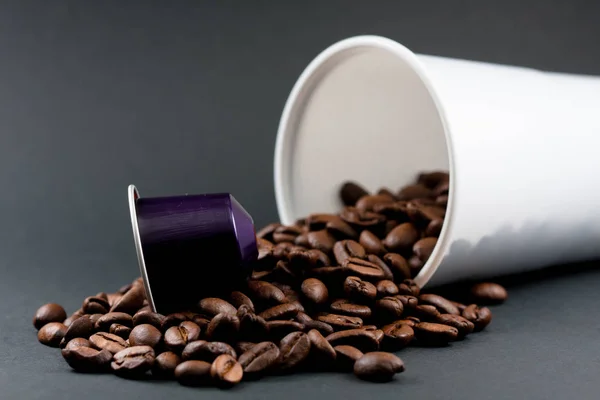 Tasse en plastique de café blanc couché, sur un fond noir, avec des grains de café brun à l'intérieur du verre. Cafétéria et nourriture . — Photo