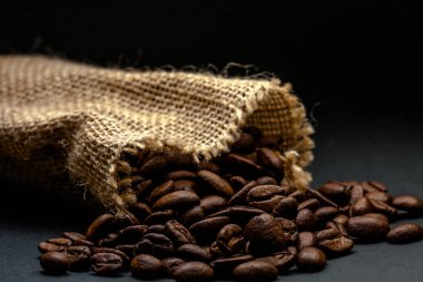 Açık sarı saman çuvalı, çuvalın içinde kahve çekirdekleri var. Siyah arka planda.