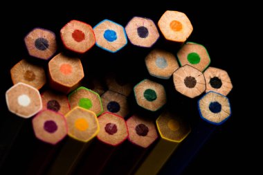 Ahşap kalemler tüm renklerde kalemlerin tabanında görülür. Renkli kalemler yığılmış. Siyah bir arka planla. Renk. Okula geri dön, eğitim.