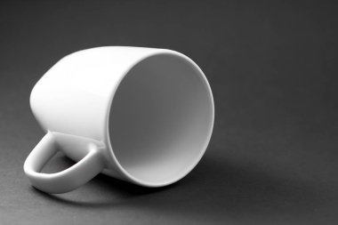 Yatay olarak yatan siyah bir arka plan üzerinde izole edilmiş beyaz bir porselen fincan şablonu.