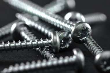 Çelik vidalar siyah bir arka plan üzerinde gruplandırılır. Diy için Araçlar.