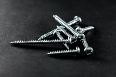 Çelik vidalar siyah bir arka plan üzerinde gruplandırılır. Diy için Araçlar.