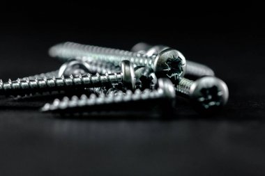 Çelik vidalar siyah bir arka plan üzerinde gruplandırılır. Diy için Araçlar.