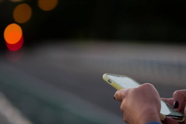 Cep telefonunda, kentsel arka planda, kadın, kentsel teknoloji de yazan kişinin elleri.