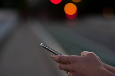 Cep telefonunda, kentsel arka planda, kadın, kentsel teknoloji de yazan kişinin elleri.