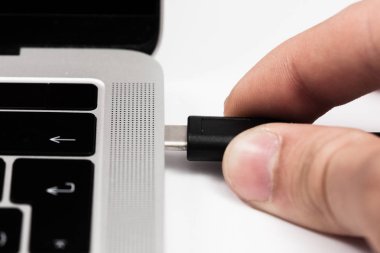 Usb kablosunu dizüstü bilgisayara takılan kişi.