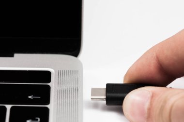 Usb kablosunu dizüstü bilgisayara takılan kişi.