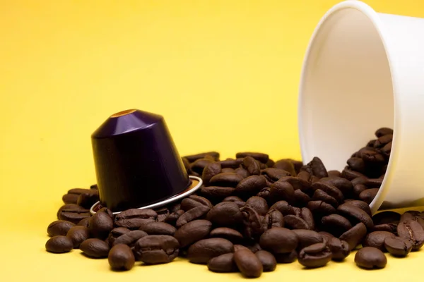 Tasse en plastique de café blanc couché, sur un fond jaune, avec des grains de café brun à l'intérieur du verre. Cafétéria et nourriture . — Photo