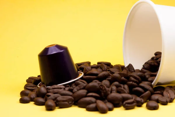 Tasse en plastique de café blanc couché, sur un fond jaune, avec des grains de café brun à l'intérieur du verre. Cafétéria et nourriture . — Photo