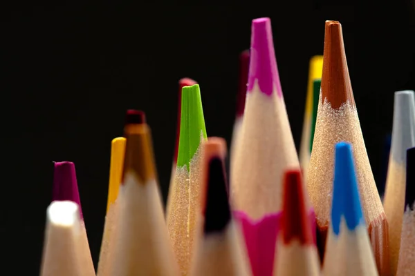 Houten potloden in alle kleuren gezien vanaf het blad van potloden. Gekleurde potloden gestapeld met een zwarte achtergrond. Kleuren. Terug naar school, onderwijs. — Stockfoto