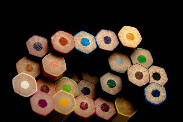 Wooden pencils in all colors seen at the base of pencils. Colored pencils stacked. With a black background.Colors. Back to school, education.