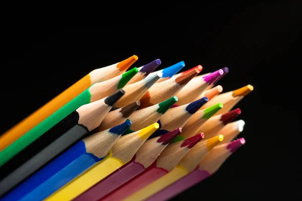 Houten potloden in alle kleuren gezien vanaf het blad van potloden. Gekleurde potloden gestapeld met een zwarte achtergrond. Kleuren. Terug naar school, onderwijs. — Stockfoto