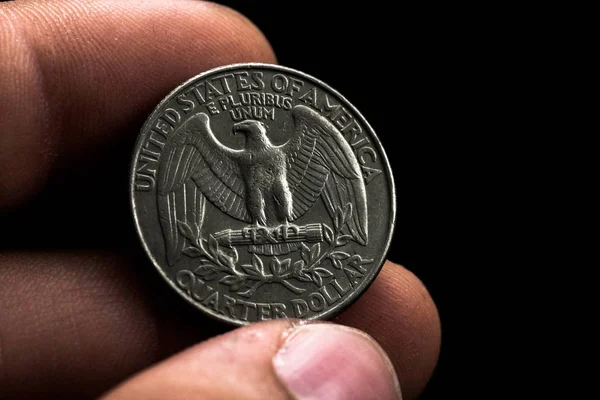 Mano de hombre sosteniendo una moneda americana de plata, primer plano de una moneda de un cuarto de dólar aislada sobre negro. Bolsa, dólares . — Foto de Stock