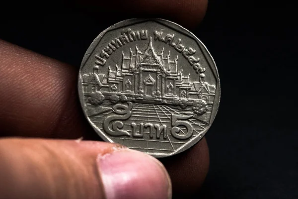 Mano de hombre sosteniendo una moneda extranjera, que muestra una cara de la moneda. Aislado sobre negro. Monedas — Foto de Stock