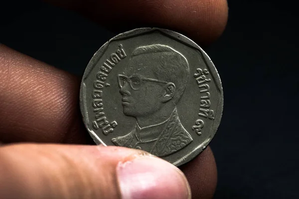 Mano de hombre sosteniendo una moneda extranjera, que muestra una cara de la moneda. Aislado sobre negro. Monedas — Foto de Stock