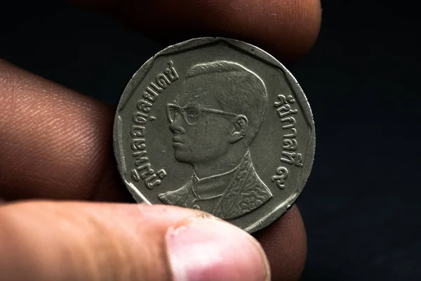 Mano de hombre sosteniendo una moneda extranjera, que muestra una cara de la moneda. Aislado sobre negro. Monedas — Foto de Stock