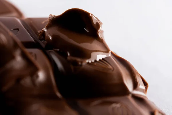 Ounces of melted chopped sweet chocolate, chocolate bars on a white background.