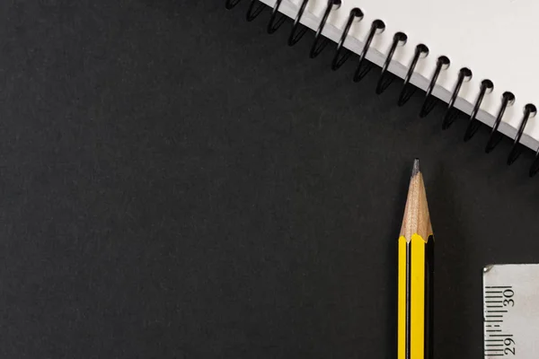 Yellow and black pencil next to a blank ring binder. Back to school.